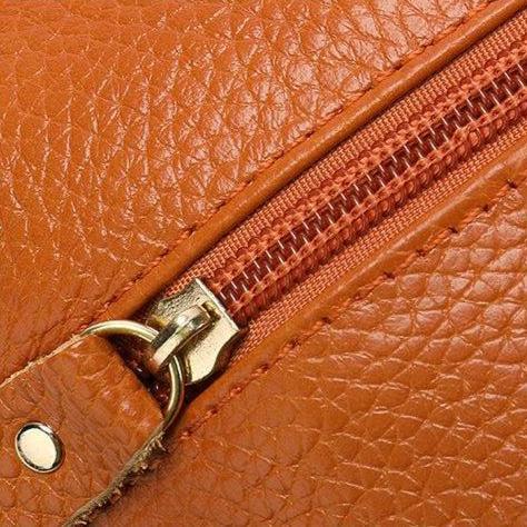 Gros plan sur la fermeture zippée du sac à bandoulière en cuir camel