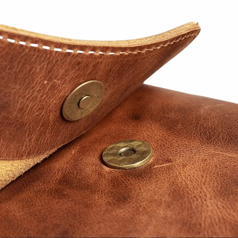 Gros plan sur la fermeture magnétique du sac bandoulière en cuir marron clair