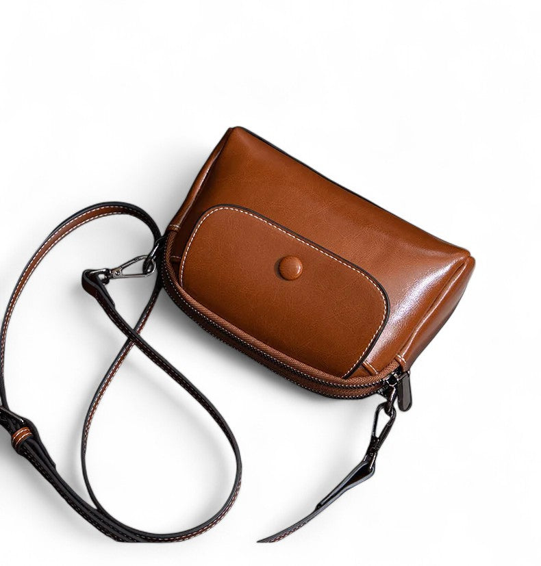 Vue d’ensemble du petit sac bandoulière en cuir marron foncé avec bandoulière ajustable.