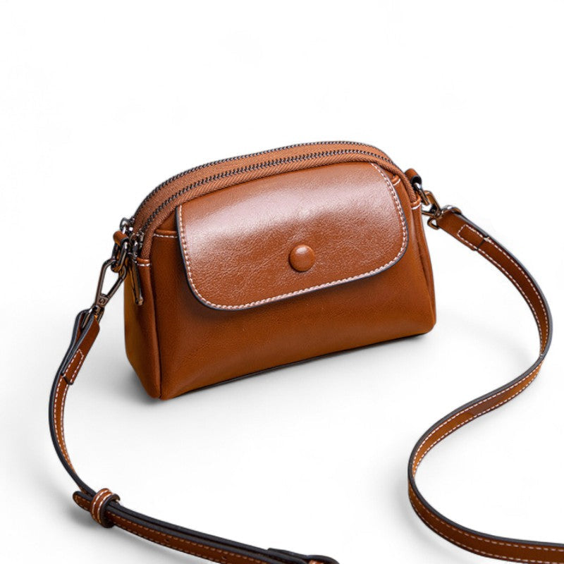 Vue de face du sac bandoulière en cuir marron foncé avec poche avant arrondie.