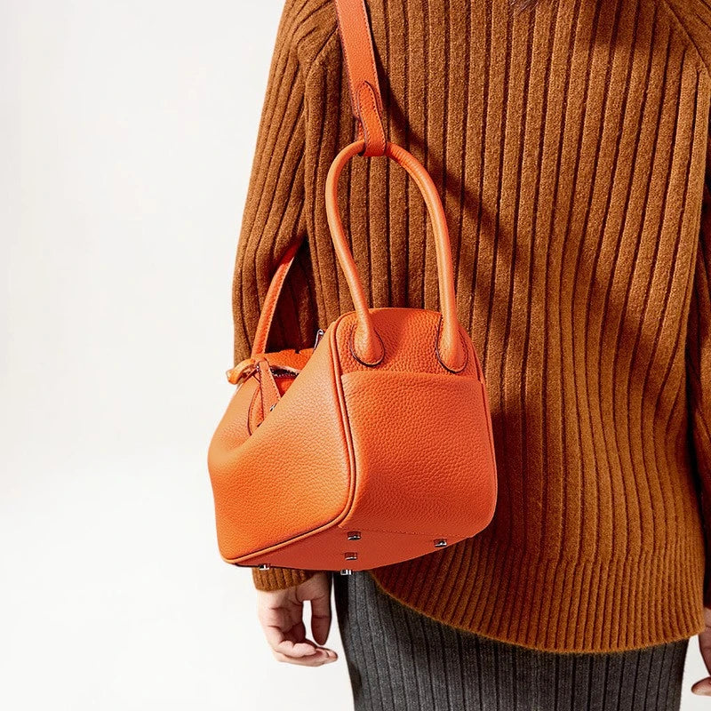 Sac bandoulière en cuir de vachette orange porté sur l'épaule