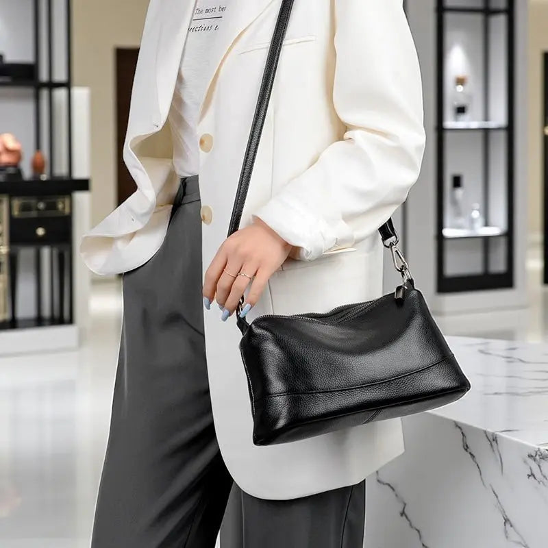 Sac bandoulière femme en cuir noir porté à l’épaule