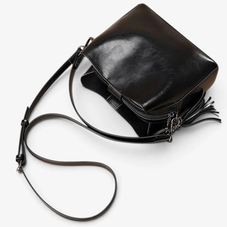 Sac bandoulière en cuir noir présenté ouvert et vu du dessus, avec fermeture zippée et bandoulière réglable.