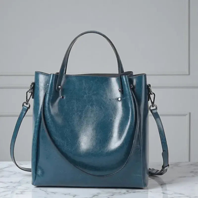 Sac cabas femme bleu en cuir véritable avec grande capacité, double poignée et bandoulière ajustable.