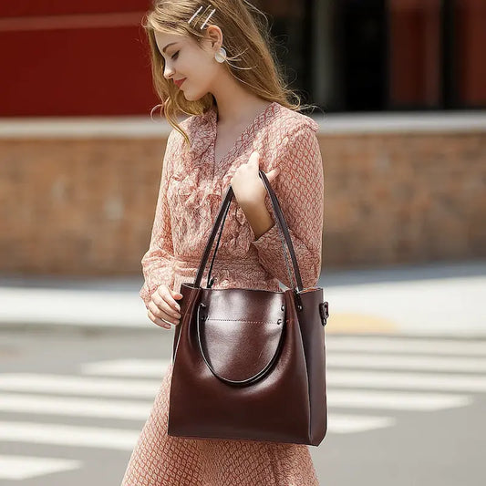 Sac cabas en cuir marron porté à l’épaule par une femme en robe rose, style chic