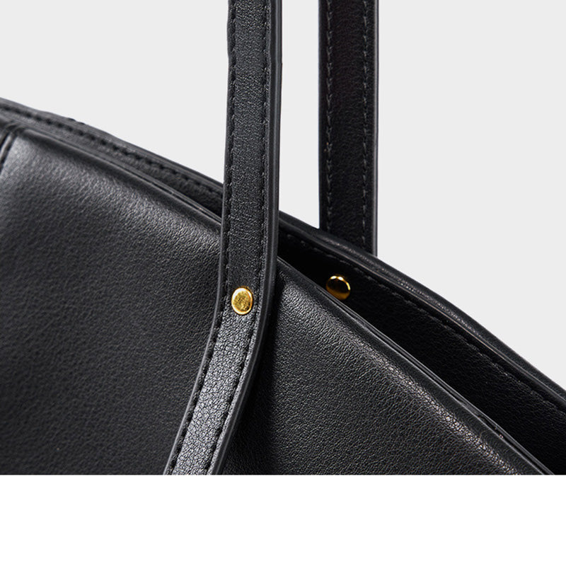 Détail des attaches du sac cabas noir avec rivets dorés et couture renforcée.