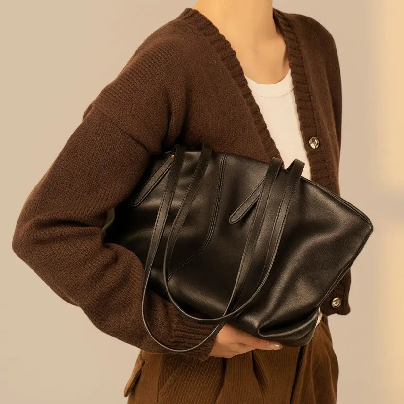 Vue du sac cabas en cuir noir porté au bras, texture lisse et silhouette structurée.