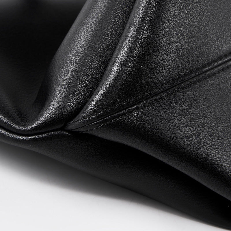 Gros plan sur les coutures apparentes du cuir noir, texture lisse et finitions précises.