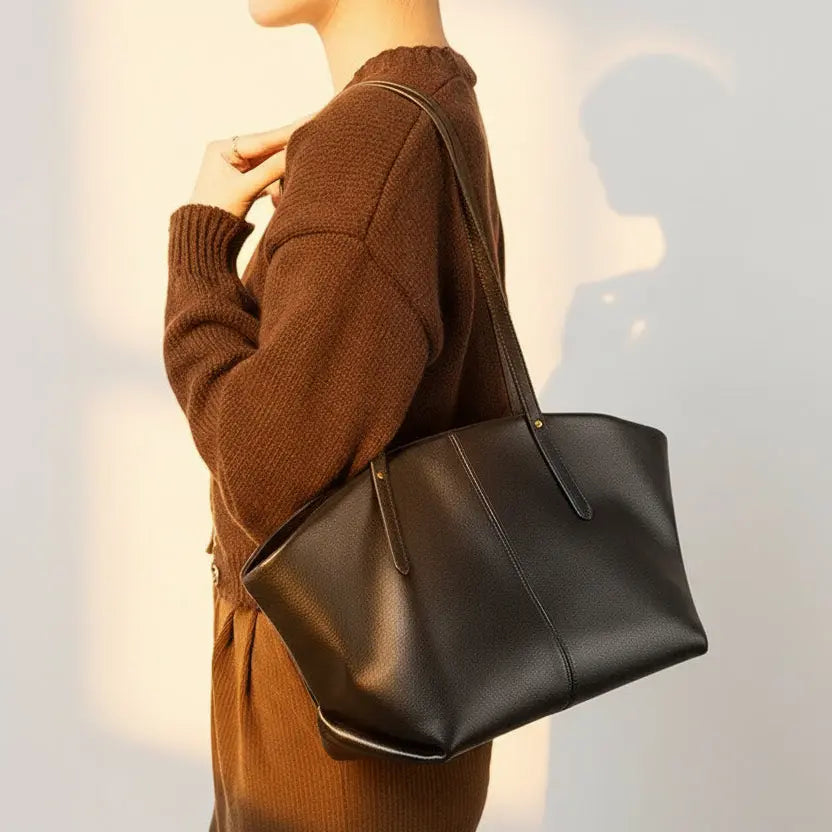 Femme portant un sac cabas en cuir noir sur l’épaule, design sobre et élégant, anses longues et souples.