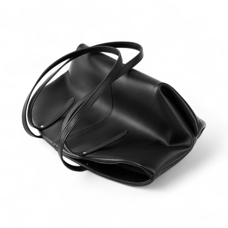 Vue du sac cabas en cuir noir vide, anses croisées sur le dessus, texture lisse et structure souple.