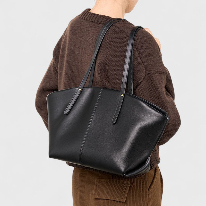 Vue arrière du sac cabas en cuir noir porté à l’épaule, lignes épurées et allure moderne.