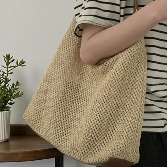 Détail du sac cabas en paille beige porté à l’épaule avec texture tressée