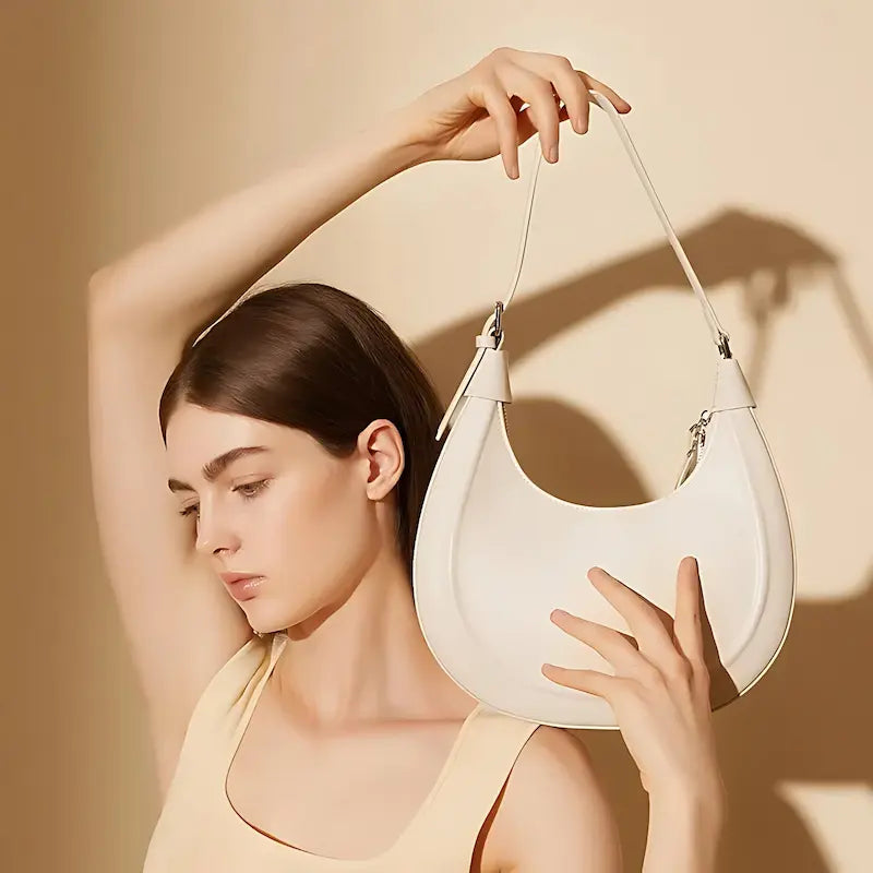 Sac croissant en cuir véritable blanc porté à l’épaule par une femme, style minimaliste