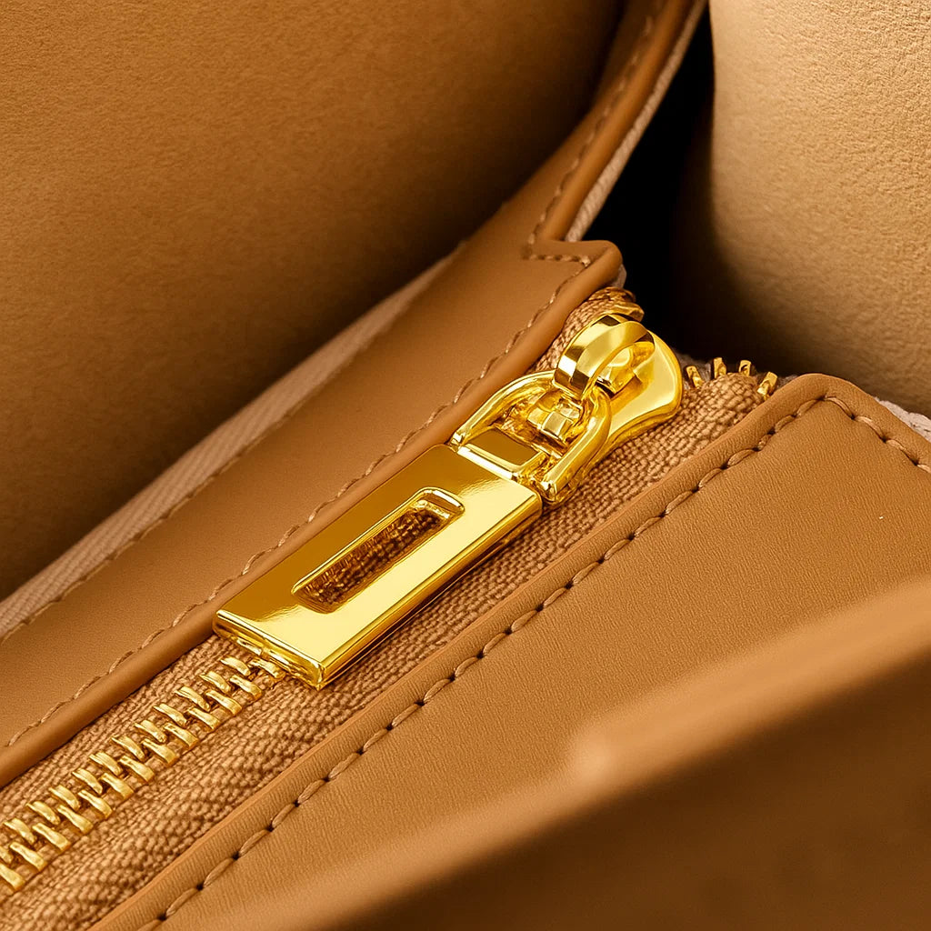 Détail de la fermeture éclair dorée du sac en cuir camel, doublure beige visible