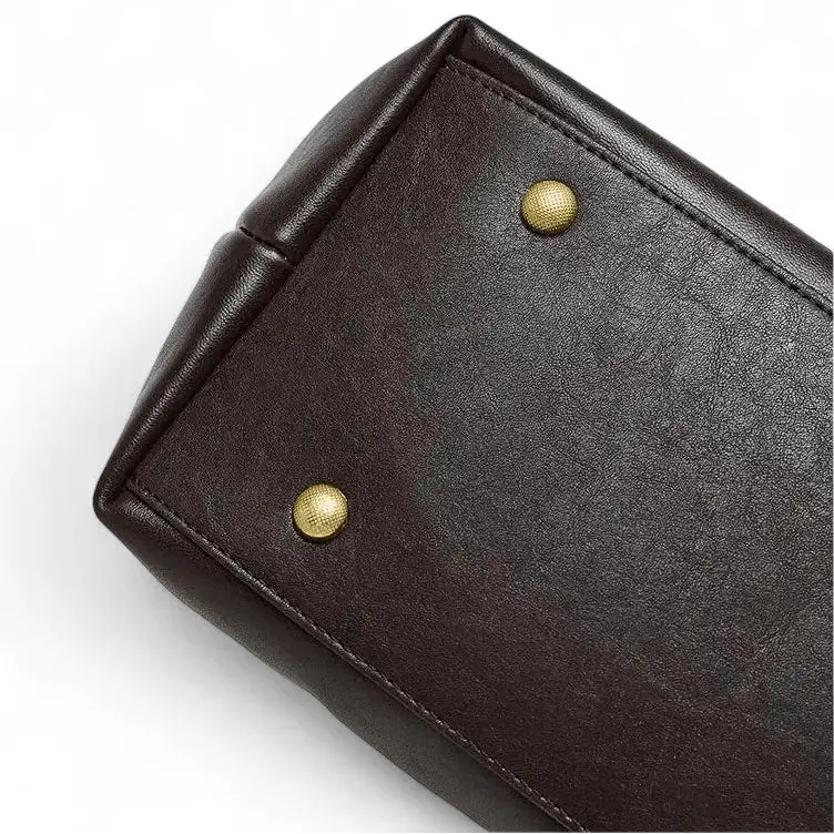 Vue du dessous du sac en cuir marron foncé avec quatre pieds métalliques dorés