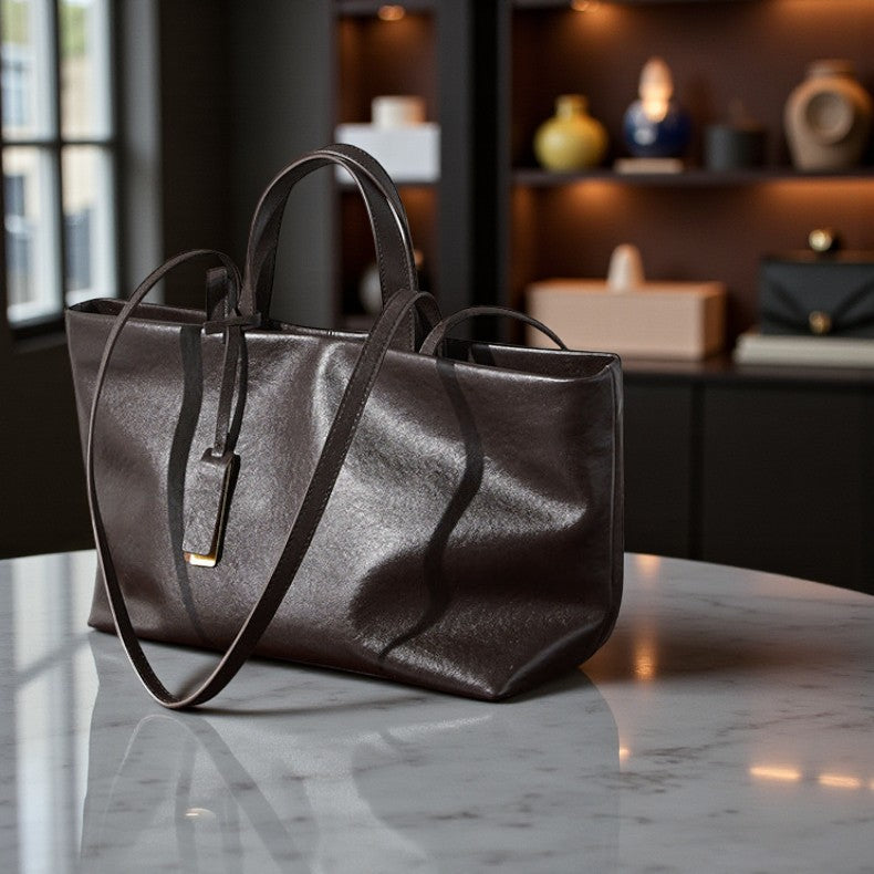 Sac en cuir noir pour femme posé sur une table claire, texture lisse et brillante