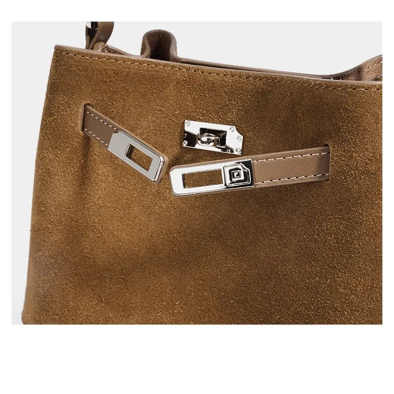 Gros plan sur la fermeture métallique d’un sac en cuir suédé camel