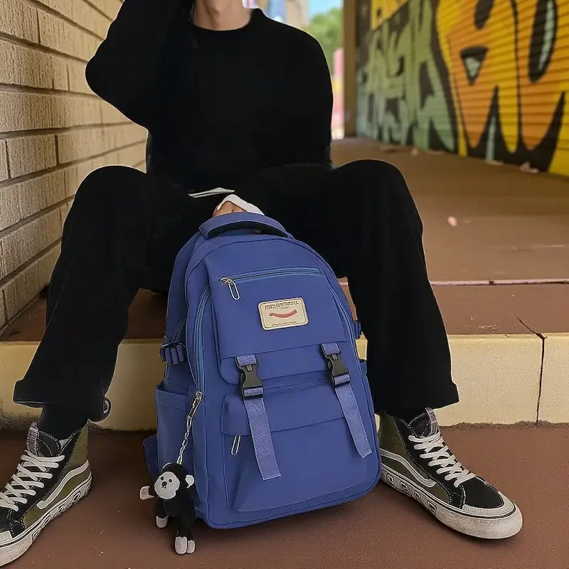 sac à dos bleu posé au sol près d’un mur graffé en extérieur
