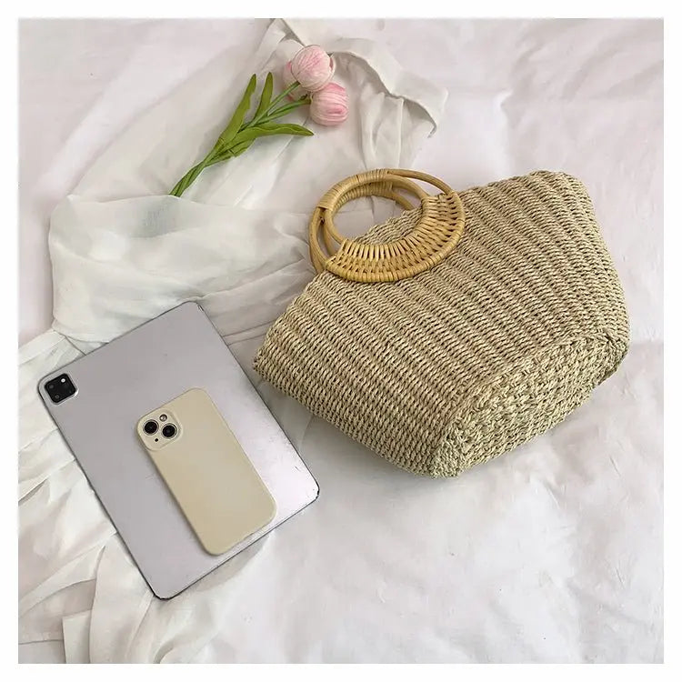 Sac en herbe tissée avec anse ronde en bois posé à côté d’un smartphone