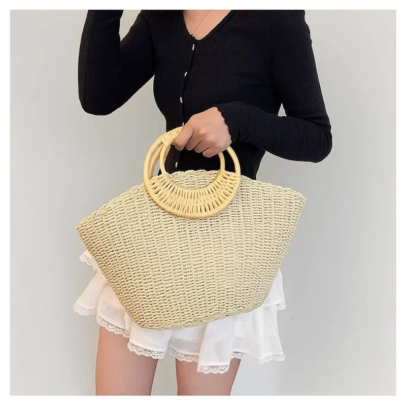 Femme en tenue blanche tenant un sac en herbe tissée avec anse ronde en bois