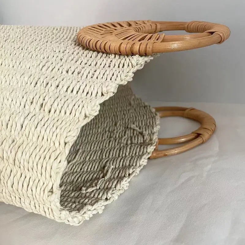 Sac en herbe tissée couché montrant son ouverture et son anse ronde