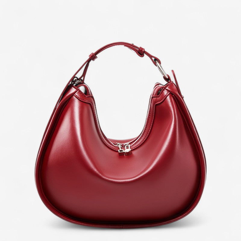 Vue de face du sac en cuir rouge de forme croissant avec anse arrondie et fermeture zippée.