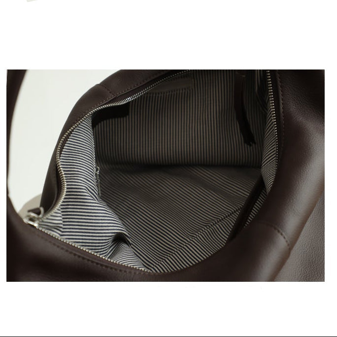 Vue de l’intérieur du sac épaule marron en cuir de vachette, doublure rayée avec poche zippée.