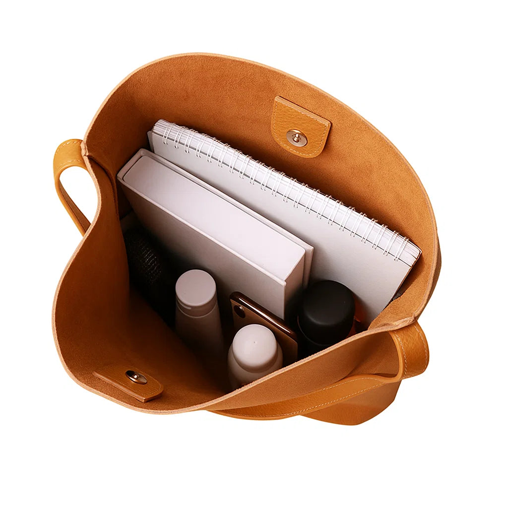 Vue intérieure du sac fourre-tout camel en cuir contenant un carnet et une bouteille