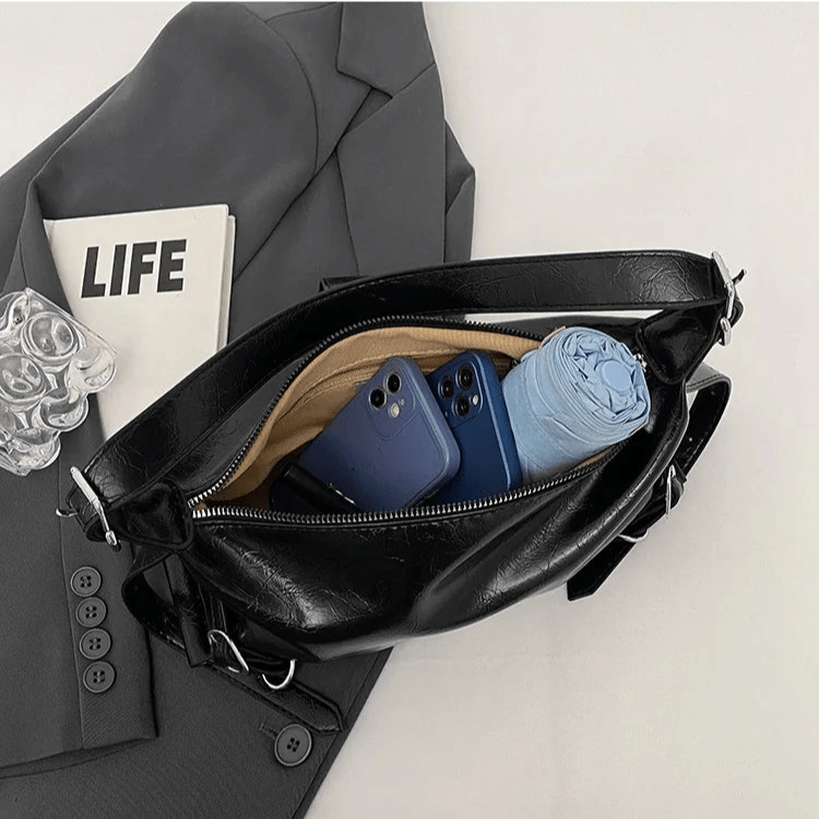 Intérieur du sac hobo en cuir synthétique vernis noir avec compartiments et objets rangés