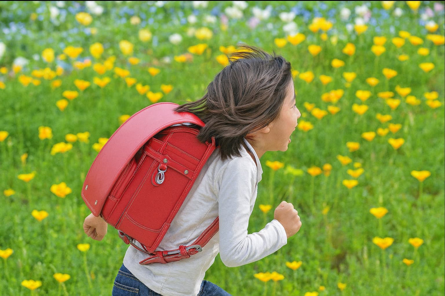 Enfant courant avec un sac japonais Randoseru rouge sur le dos dans un champ fleuri