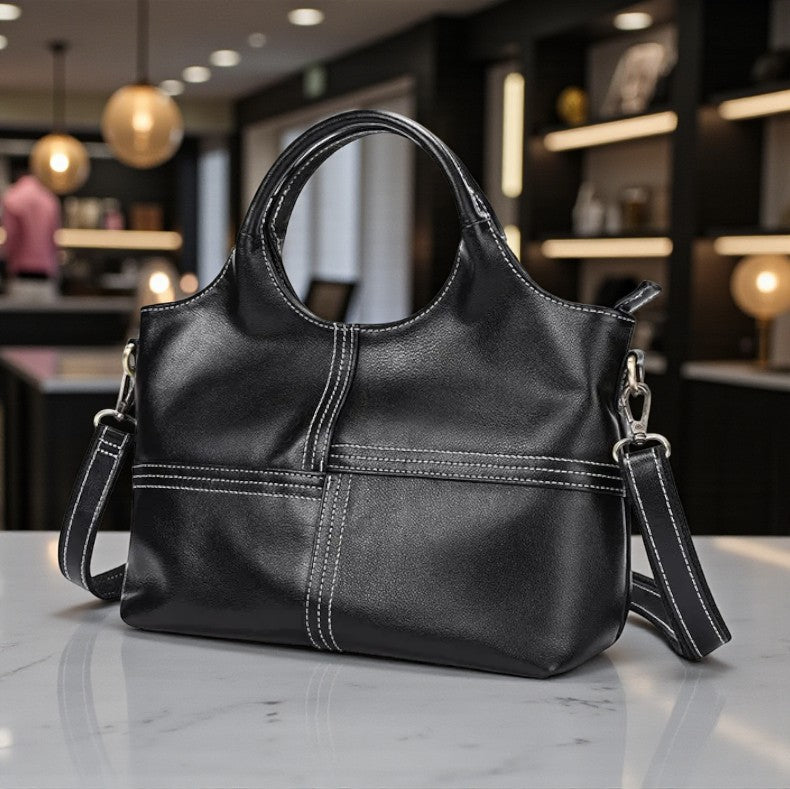 Sac à main noir en cuir véritable posé sur une table, ambiance élégante et moderne.