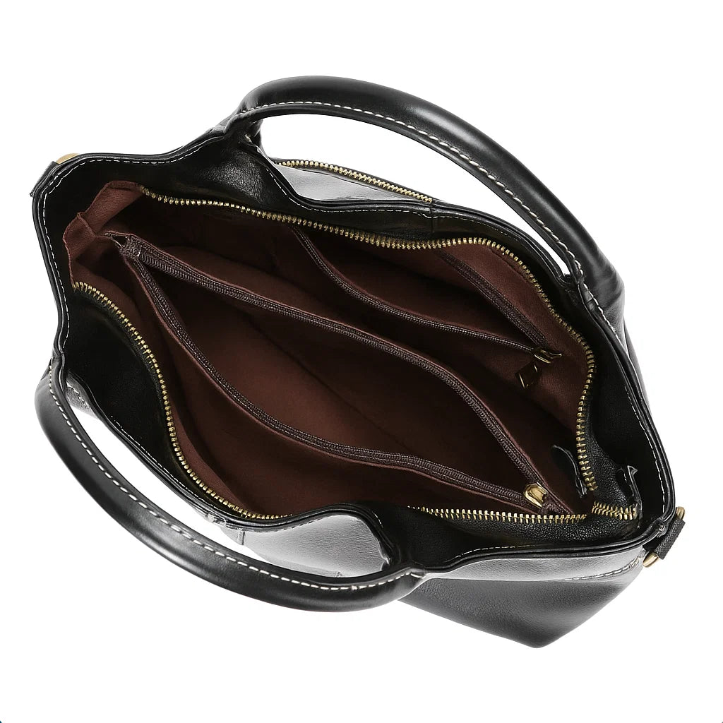 Vue intérieure du sac à main en cuir noir avec compartiments doublés et fermeture éclair.
