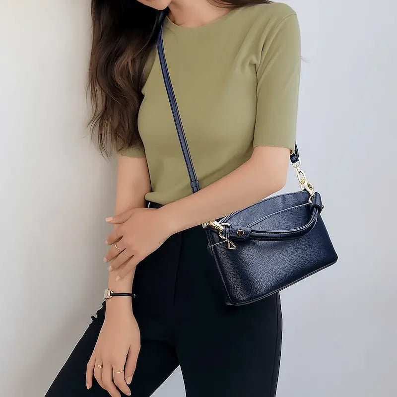 Sac à main rectangulaire en cuir de vachette bleu marine porté en bandoulière par une femme