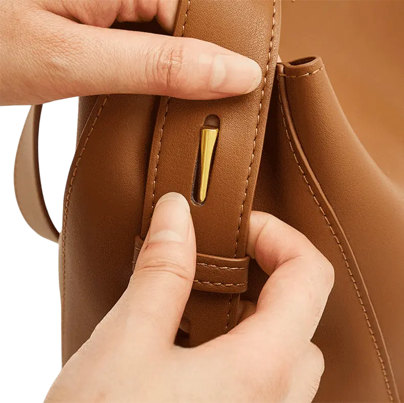 Gros plan sur la fermeture dorée du sac messager camel en cuir, montrant la finition précise.