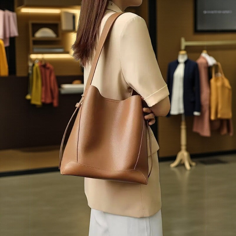 Femme portant un sac messager camel en cuir dans un intérieur moderne avec éclairage doux.