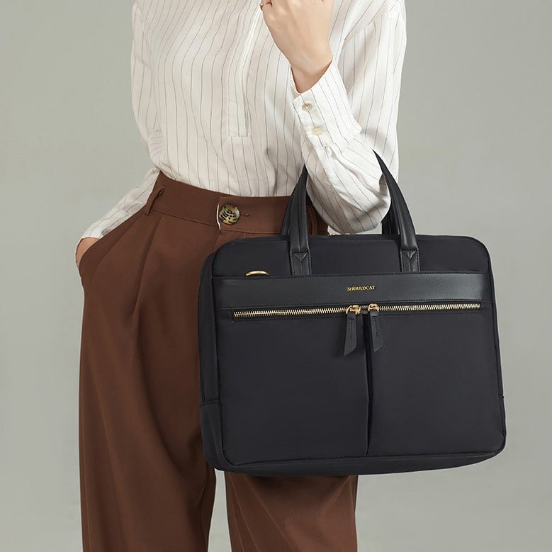 Sac ordinateur noir porté à la main par une femme en tenue professionnelle