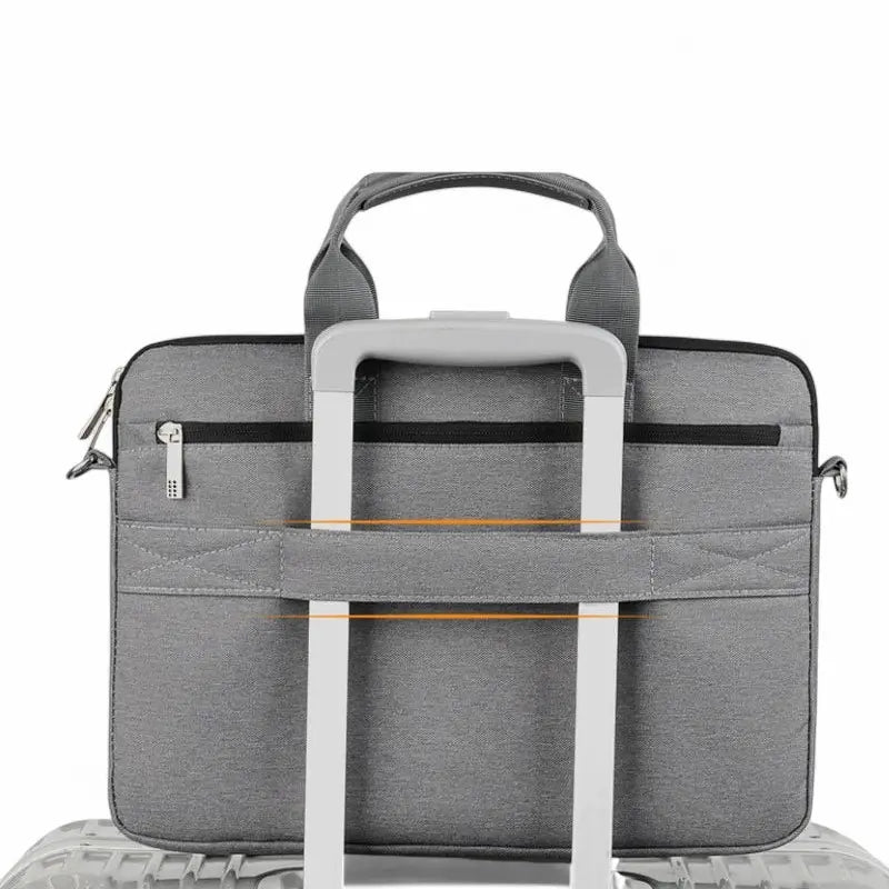 Sac pour ordinateur portable gris avec sangle arrière fixée à une valise