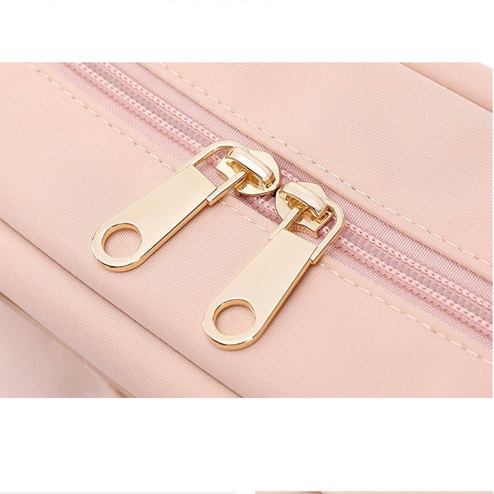 Détail des fermetures éclair dorées sur un sac ordinateur rose clair