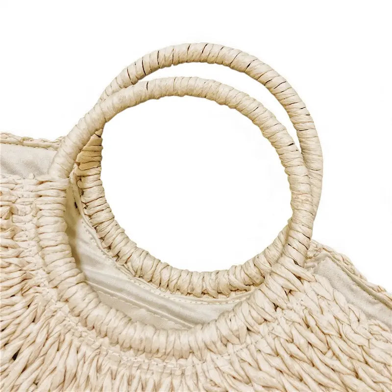 Gros plan des anses rondes rigides du sac en paille forme coquillage