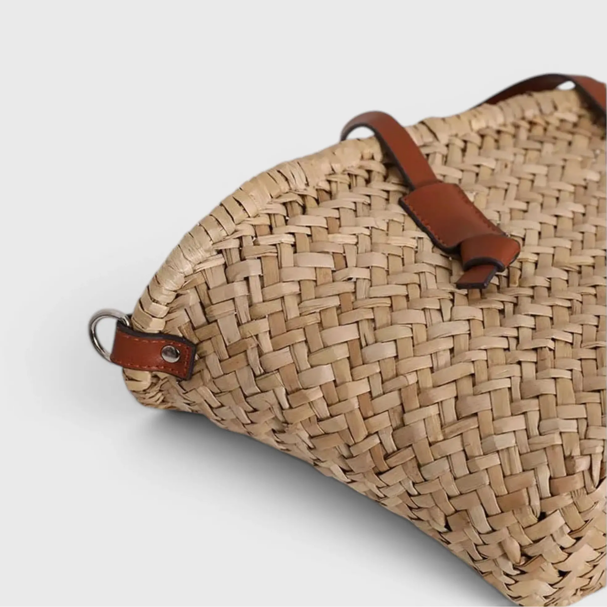 détail sac en paille tressée avec finition cuir et attaches latérales