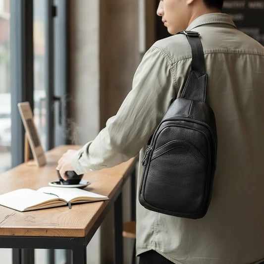 Sac de poitrine en cuir noir porté dans le dos par un homme en chemise beige