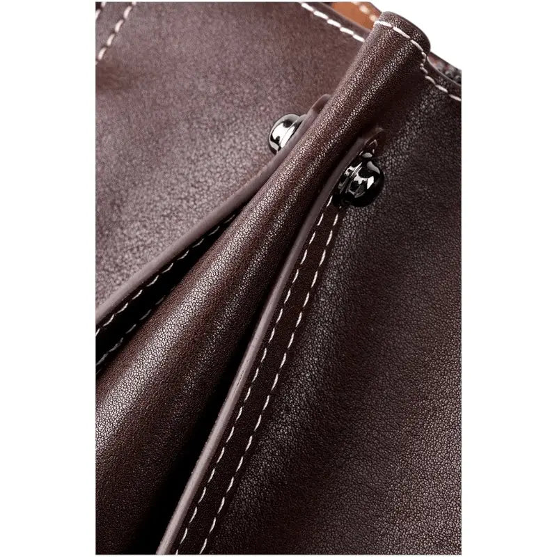 Gros plan sur la fermeture et les attaches du sac porté épaule en cuir marron.