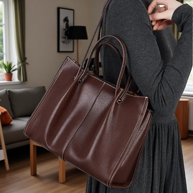 Sac en cuir marron porté épaule par une femme dans un intérieur moderne et lumineux.