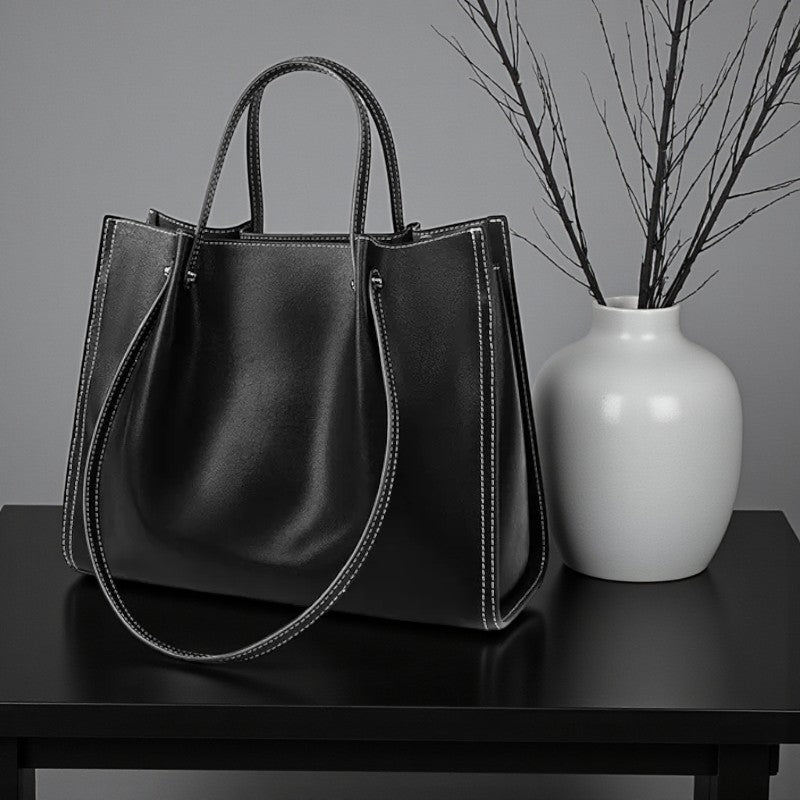 Sac en cuir noir posé sur une table avec vase décoratif dans un cadre minimaliste.