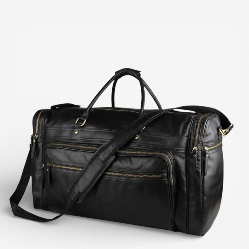 Sac de voyage noir en cuir pleine fleur photographié en studio, avec bandoulière visible en premier plan