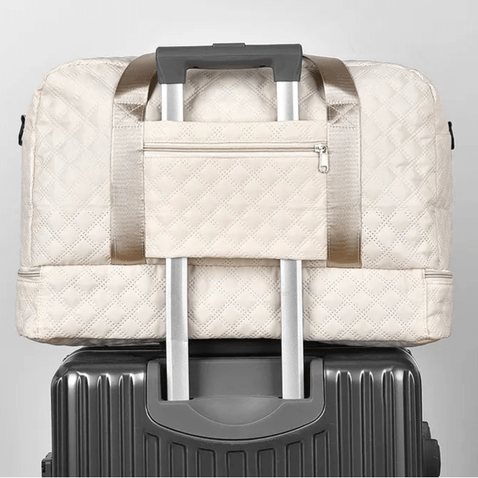 Sac de voyage femme beige fixé sur une valise grâce à la bande arrière