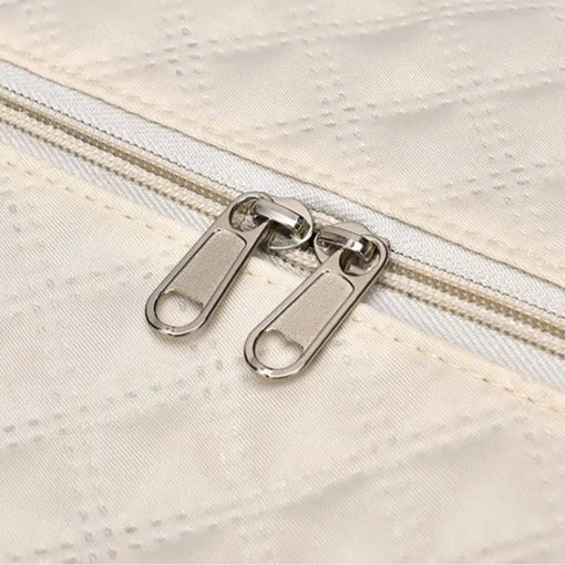 Détail de la fermeture éclair double curseur d’un sac de voyage femme beige