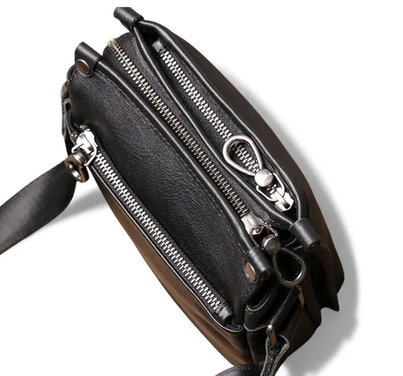 Vue latérale de la sacoche en cuir noire montrant les compartiments à fermeture éclair