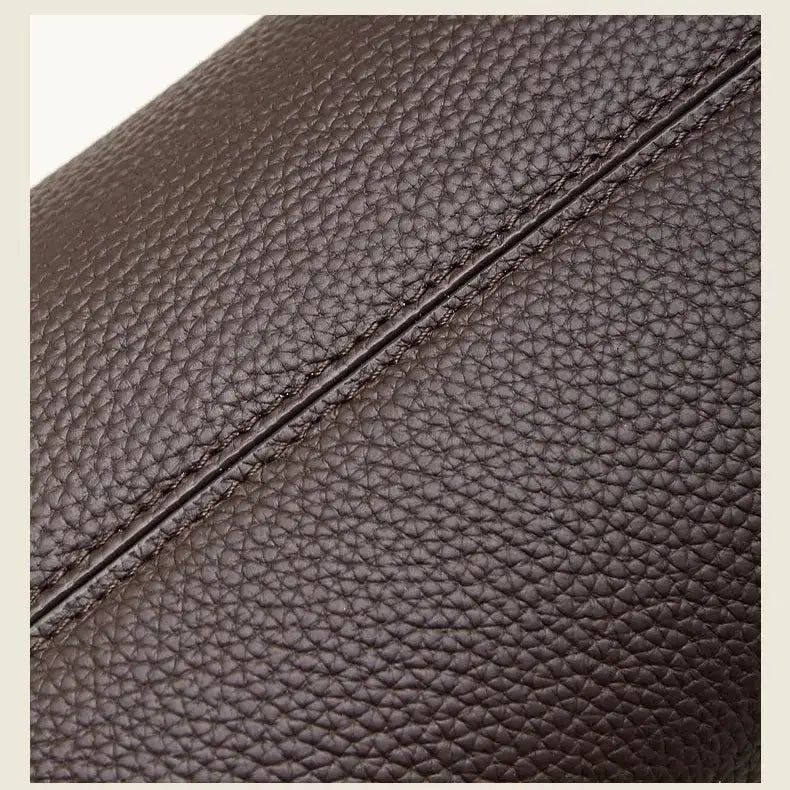 Gros plan sur la texture du cuir grainé marron et les coutures du sac bowling