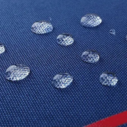 Détail du tissu imperméable du sac à dos bleu et rouge avec gouttes d’eau en surface